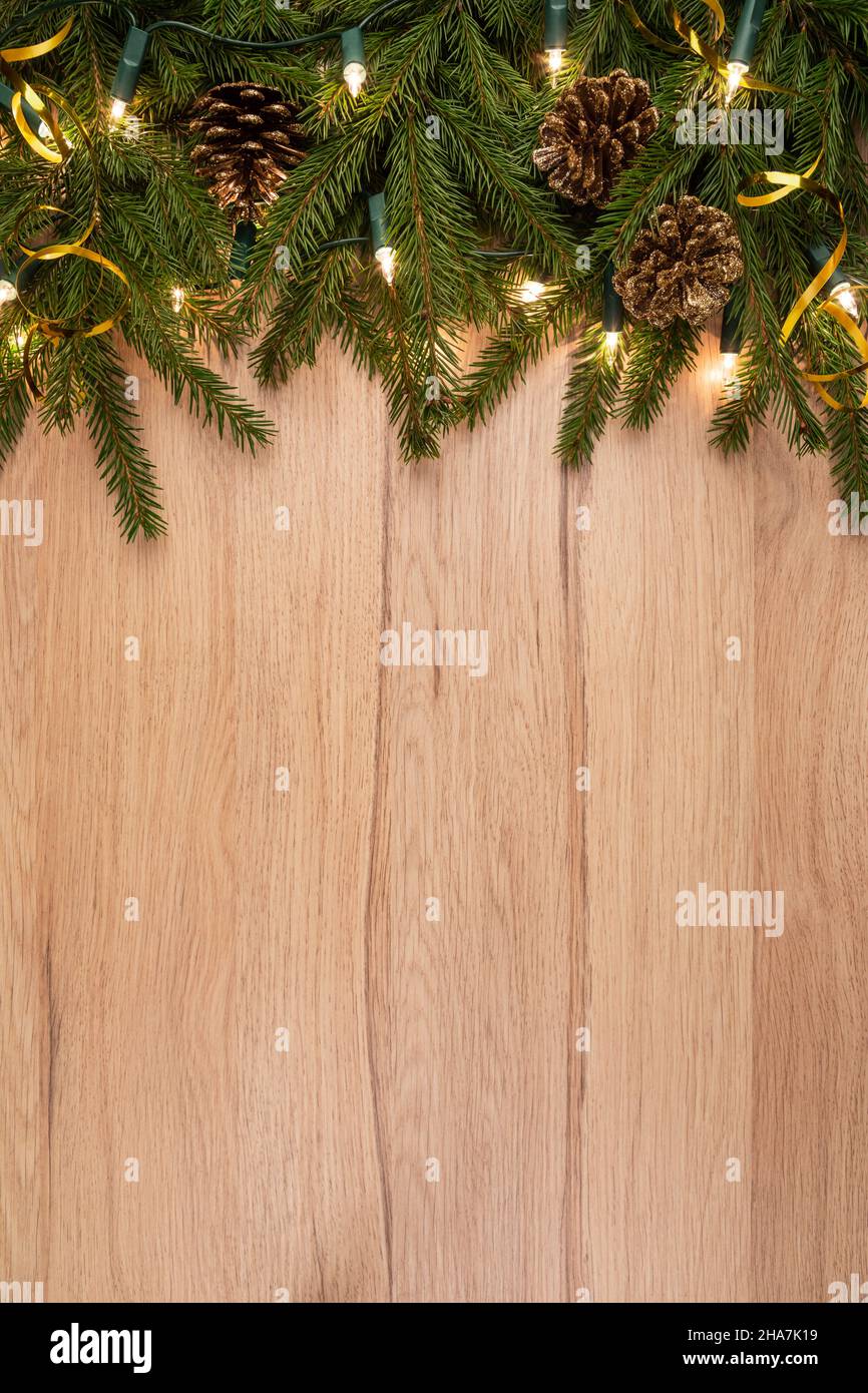 Christmas background with fir branches cones and lights on wooden board ...