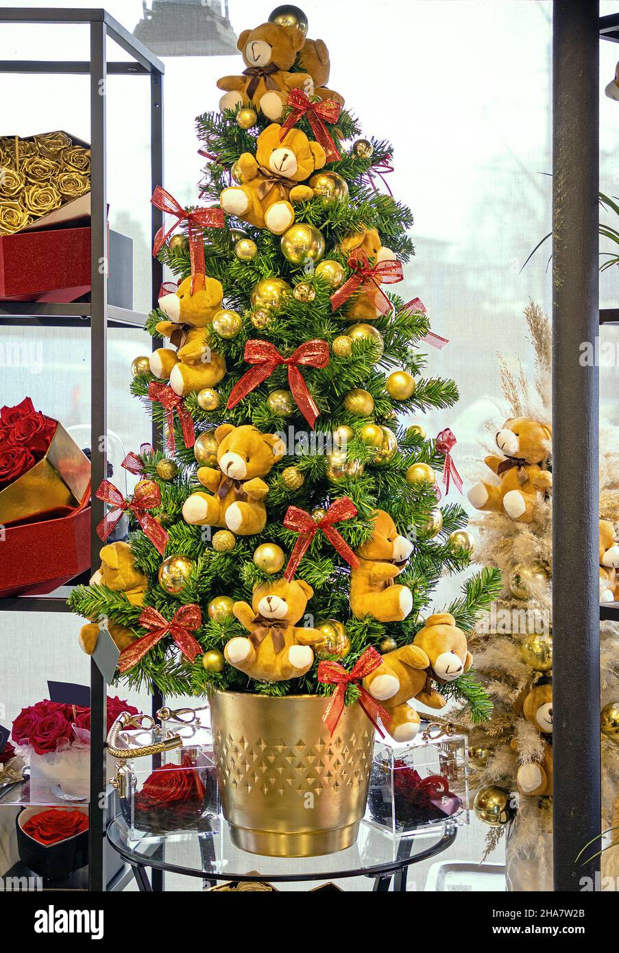 Festive Christmas tree decorated with red bows and teddy bear stuffed toys  in gold pot Stock Photo - Alamy