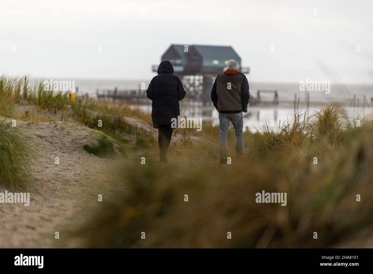 St. Peter Ording, Germany. 11th Dec, 2021. Walkers go for a stroll on the North Sea beach during rainy weather. Credit: Philipp Schulze/dpa/Alamy Live News Stock Photo