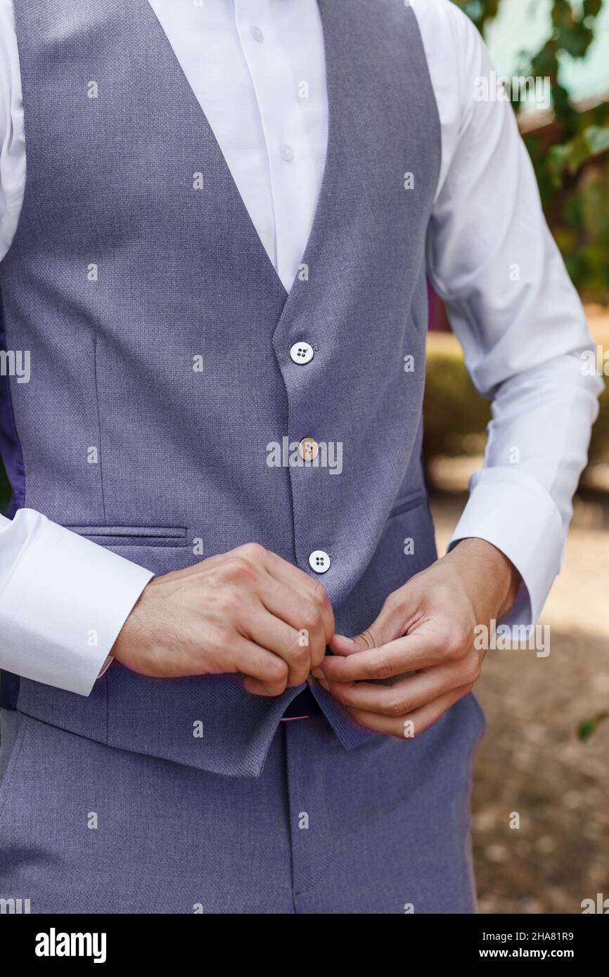 Man in Very Peri suit fastens the buttons of the jacket, close-up. Gentleman getting ready in the morning. Trendy color of the year 2022 in clothing. Stock Photo