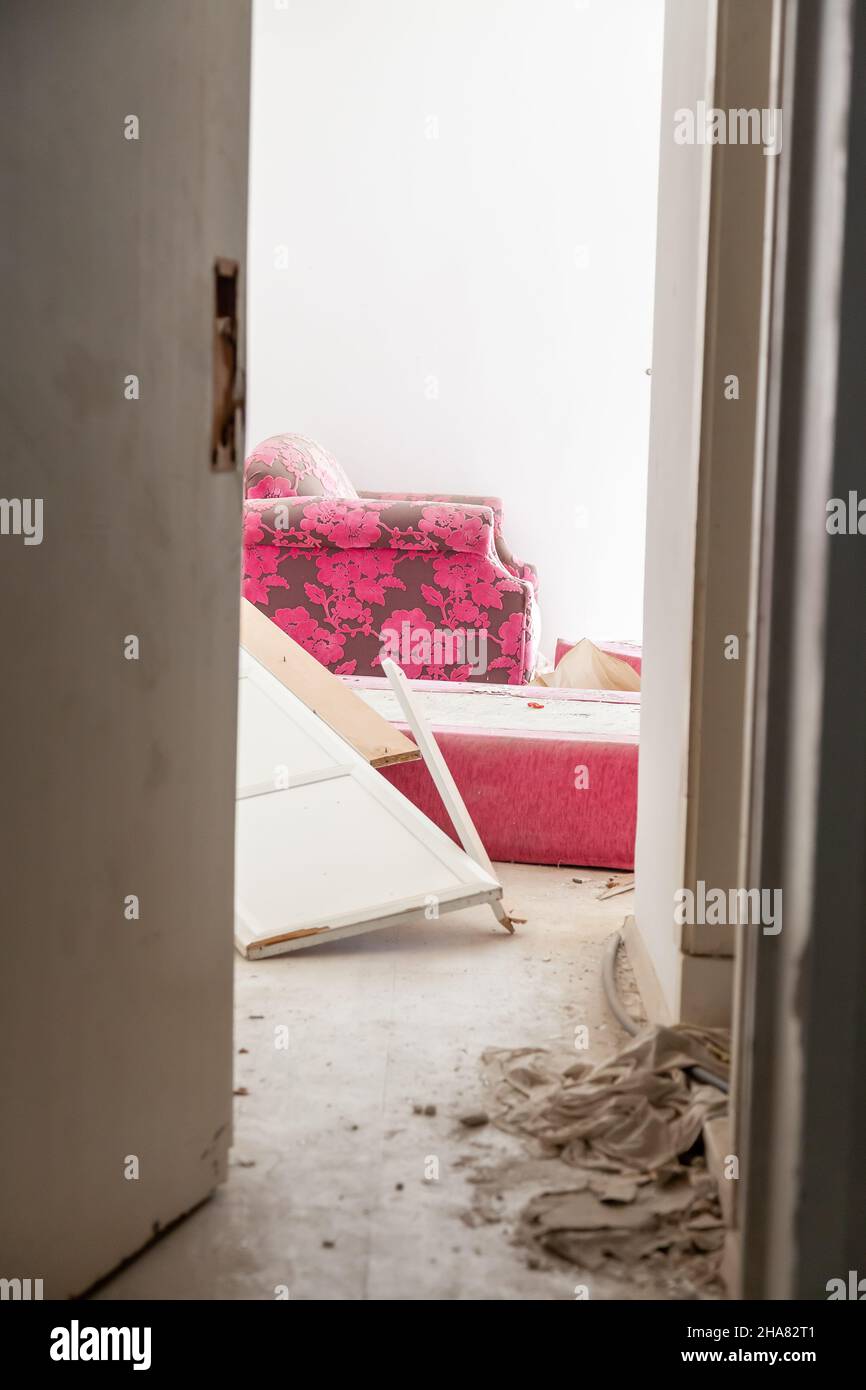 Pieces of broken glass among destroyed furniture and door in an