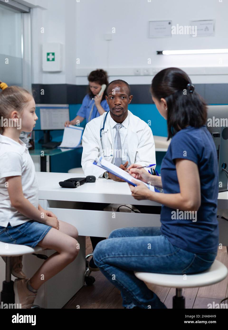 Patient mother writing medical accord on document while discussing sickness expertise with