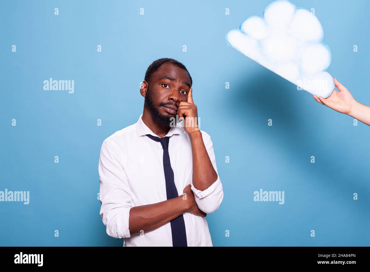 Professional businessman thinking under white paper thought bubble concept standing with arms crossed and finger pointing at head. African american entrepreneur brainstorming next to idea cloud. Stock Photo