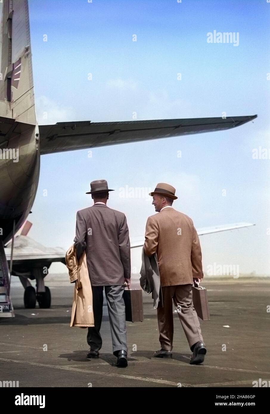 1950s TWO MEN BUSINESSMEN WEARING HATS CARRYING OVERCOATS AND BRIEFCASES WALKING TOGETHER TO BOARD PROPELLER AIRLINER - a3136c DEB001 HARS SALESPERSON PASSENGERS JOBS FLIGHT GROWNUP PASSENGER TRANSPORT COPY SPACE FRIENDSHIP FULL-LENGTH GROWN-UP MALES WINGS CONFIDENCE EXECUTIVES TRANSPORTATION WHITE COLLAR WING OCCUPATION SELLING WALKS TWO MEN CAREERS TOWARD TARMAC REAR VIEW AVIATION OCCUPATIONS BUSINESS MAN BUSINESS MEN BUSINESS PEOPLE CONNECTION FROM BEHIND BUSINESSPEOPLE BUSINESSPERSON MOBILITY TRANSPORTS DEB001 MALE BONDING BACK VIEW COMMERCIAL AVIATION MID-ADULT PROFESSIONALS SALESMEN Stock Photo