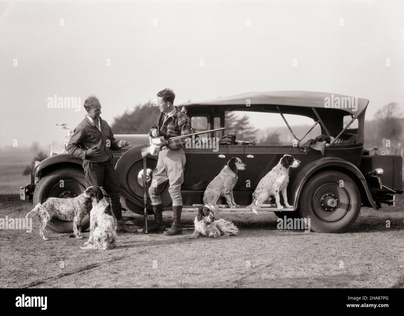 1920s 1930s TWO MEN UPLAND GAME BIRD HUNTERS STANDING BY PACKARD CONVERTIBLE TOURING CAR WITH SHOT GUNS AND FIVE SPORTING DOGS - g3769 HAR001 HARS ATHLETE LIFESTYLE SHOT FIVE 5 RURAL LUXURY COPY SPACE FRIENDSHIP FULL-LENGTH PERSONS AUTOMOBILE MALES ATHLETIC HUNTER TRANSPORTATION MIDDLE-AGED B&W HUNT MIDDLE-AGED MAN SPORTING MAMMALS ADVENTURE LEISURE AND AUTOS CANINES RECREATION BY POOCH AUTOMOBILES STYLISH VEHICLES UPLAND CANINE FIREARM FIREARMS HUNTERS MAMMAL MID-ADULT MID-ADULT MAN PACKARD RETRIEVING BLACK AND WHITE CAUCASIAN ETHNICITY HAR001 OLD FASHIONED TOURING Stock Photo