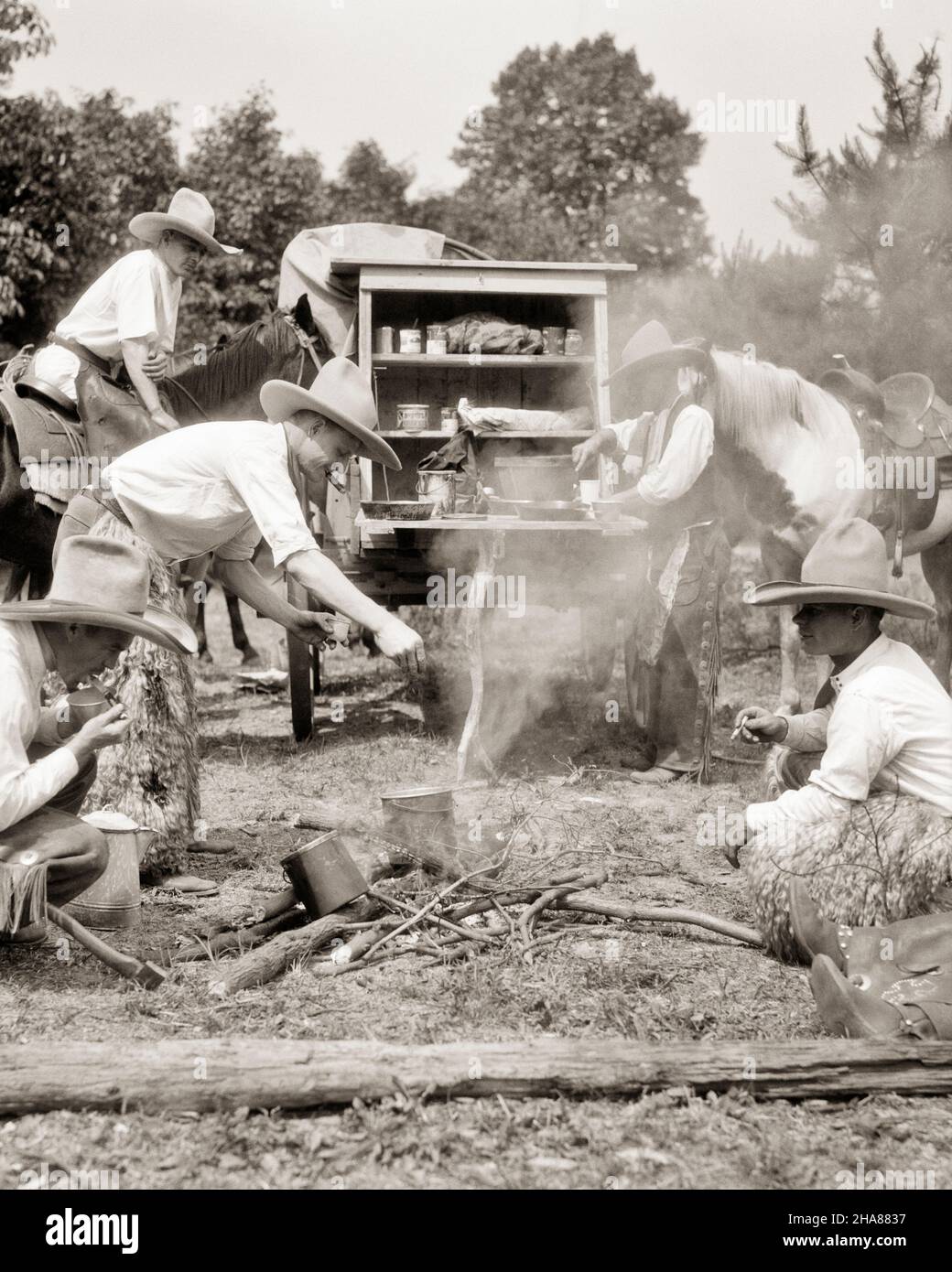 1930s WESTERN MEN RANCH HAND COWBOYS COOKING AND EATING GATHERED AROUND CAMPFIRE BESIDE A CHUCK WAGON ALL WEARING 10 GALLON HATS - h1161 HAR001 HARS COPY SPACE FRIENDSHIP FULL-LENGTH PERSONS CHARACTER MALES WESTERN ALL BEANS CAMPFIRE B&W COWBOYS MAMMALS ADVENTURE LEISURE AND NUTRITION RECREATION A OCCUPATIONS GALLON CONCEPTUAL 10 BESIDE CONSUME CONSUMING NOURISHMENT RANCH HAND GATHERED MAMMAL MID-ADULT MID-ADULT MAN RELAXATION TOGETHERNESS YOUNG ADULT MAN BLACK AND WHITE HAR001 OLD FASHIONED Stock Photo