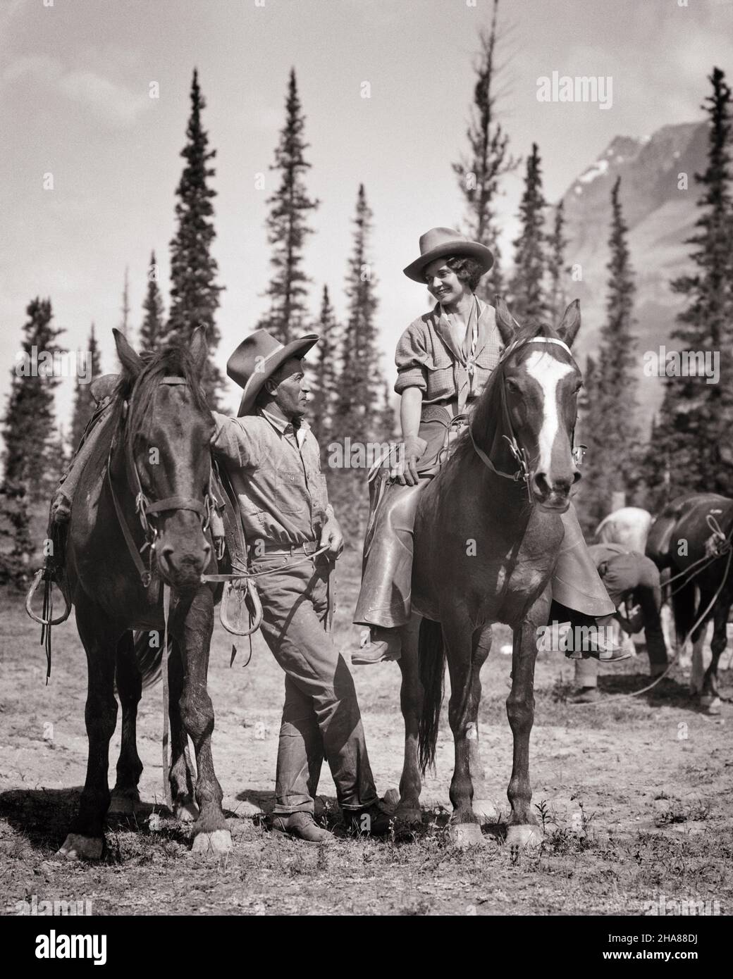 1920s 1930s OLDER MAN RANCH HAND COWBOY STANDING BY HORSE TALKING TO MOUNTED YOUNG WOMAN COWGIRL RIDING AT WESTERN DUDE RANCH - h4008 HAR001 HARS BEAUTY OLD TIME NOSTALGIA OLD FASHION 1 COMMUNICATION YOUNG ADULT HORSES BALANCE MONTANA TEAMWORK VACATION PLEASED JOY LIFESTYLE CELEBRATION FEMALES JOBS RURAL UNITED STATES COPY SPACE FULL-LENGTH LADIES PERSONS INSPIRATION SADDLE UNITED STATES OF AMERICA MALES WESTERN CONFIDENCE MIDDLE-AGED B&W NORTH AMERICA MIDDLE-AGED MAN NORTH AMERICAN TIME OFF SKILL OCCUPATION SKILLS MAMMALS CHEERFUL ADVENTURE LEISURE CUSTOMER SERVICE TRIP GETAWAY KNOWLEDGE Stock Photo