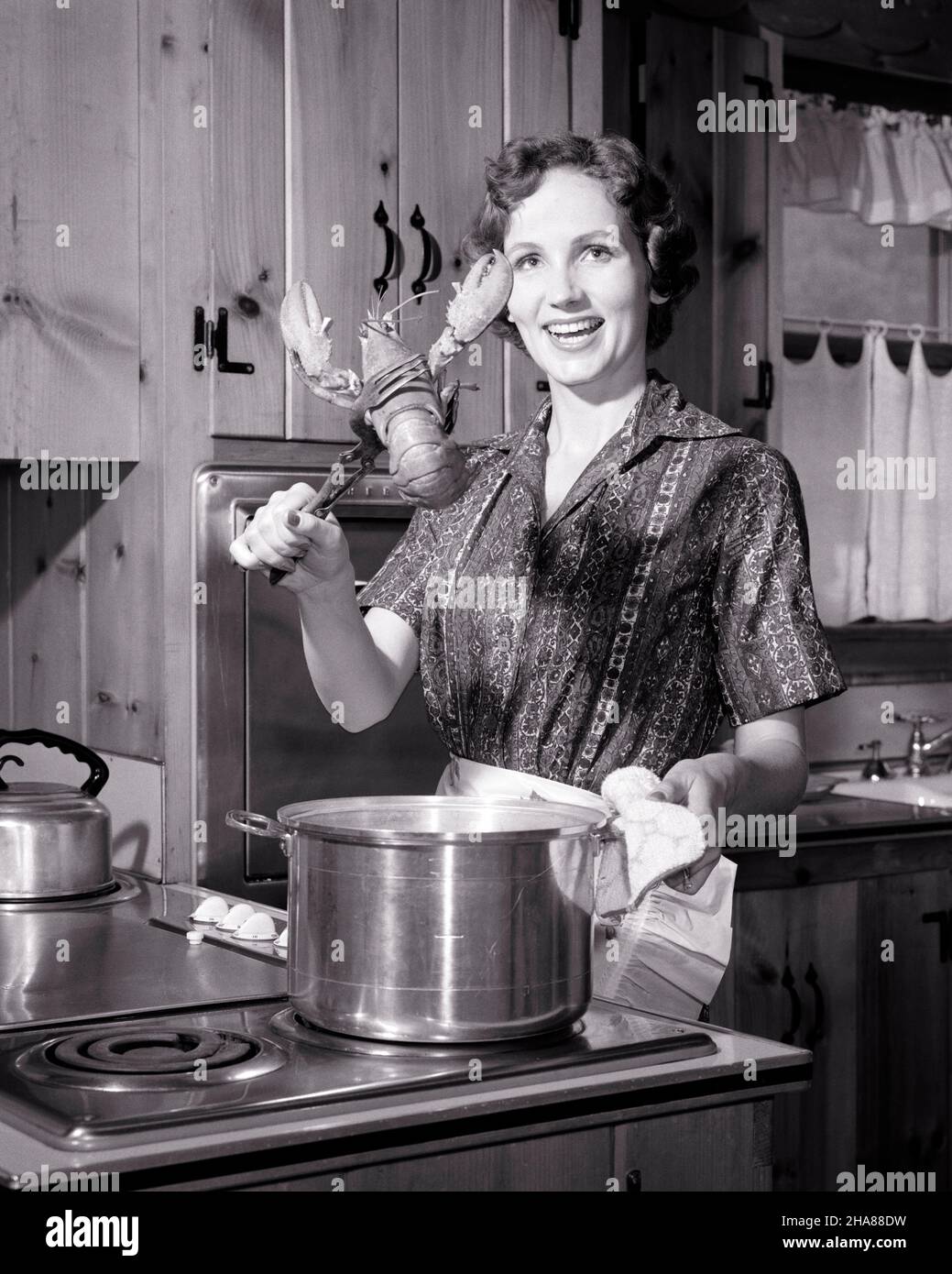 1950s 1960s SMILING WOMAN HOUSEWIFE LOOKING AT CAMERA COOKING DINNER ABOUT TO PUT LOBSTER INTO POT OF BOILING WATER ON STOVE - h3314 DEB001 HARS HOME LIFE LUXURY PREPARING HALF-LENGTH LADIES PERSONS ABOUT EXPRESSIONS B&W EYE CONTACT HOMEMAKER PUT HOMEMAKERS CHEERFUL CHOICE IN INTO OF ON TO HOUSEWIVES SMILES CONCEPTUAL BOILING JOYFUL STYLISH DEB001 YOUNG ADULT WOMAN BLACK AND WHITE CAUCASIAN ETHNICITY OLD FASHIONED Stock Photo