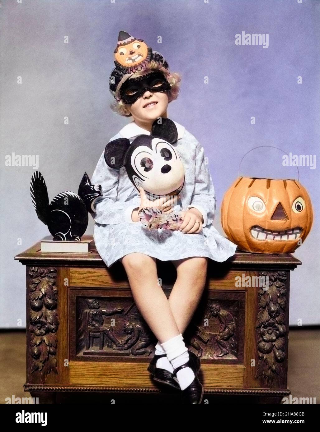 1930s LITTLE GIRL HOLDING MICKEY MOUSE TOY WEARING MASK CLOWN HAT LOOKING AT CAMERA SITTING BESIDE BLACK CAT HALLOWEEN PUMPKIN - h4264c HAR001 HARS STUDIO SHOT MASKS HEALTHINESS HOME LIFE COPY SPACE HALF-LENGTH AMERICANA EYE CONTACT HAPPINESS EXCITEMENT POSING MOUSE BESIDE ANONYMOUS OCTOBER JUVENILES MARY JANE SHOES MASKED MICKEY MICKEY MOUSE POSE CAUCASIAN ETHNICITY HAR001 OLD FASHIONED Stock Photo