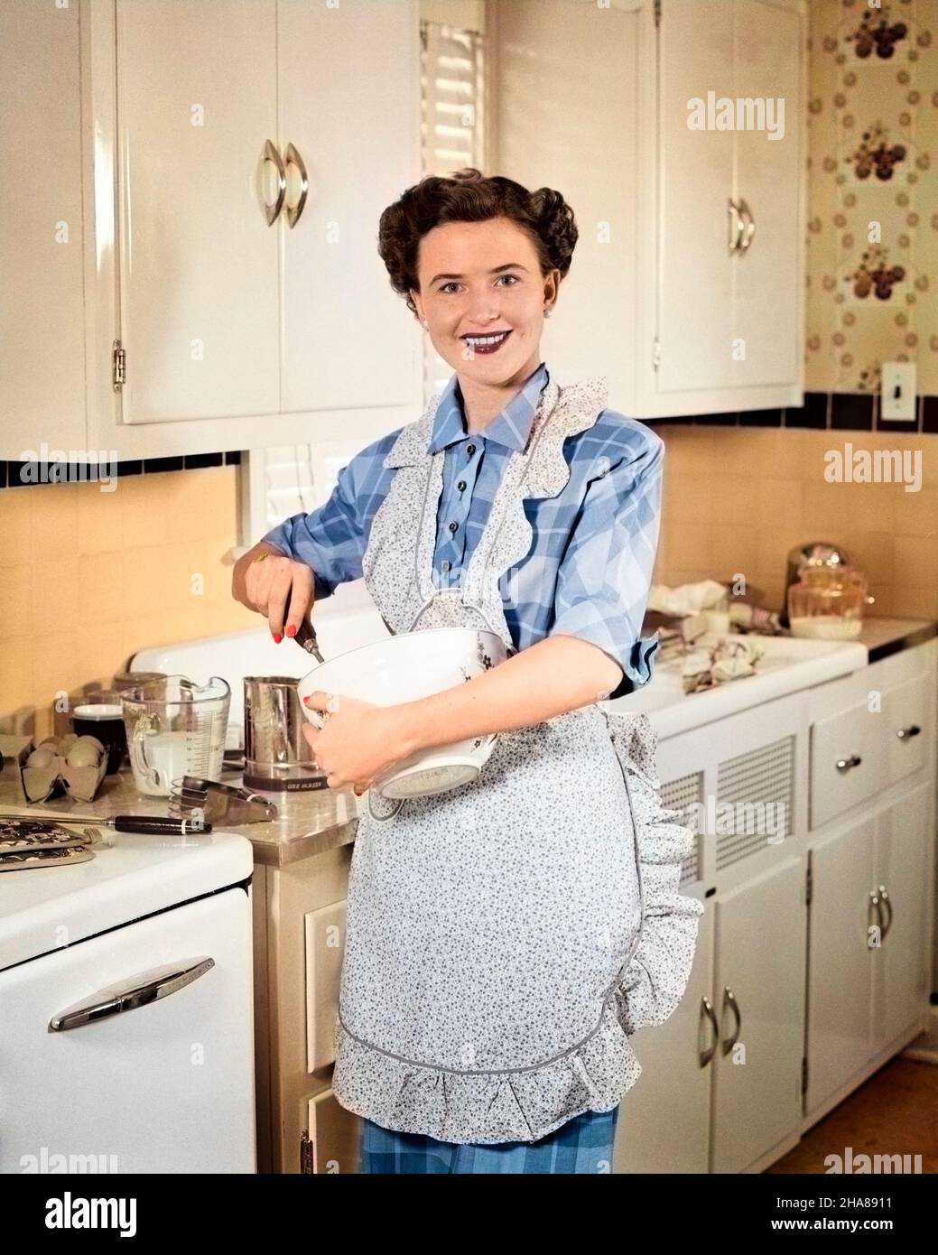 1950s WOMAN HOUSEWIFE IN KITCHEN APRON MIXING BAKING INGREDIENTS IN BOWL  Stock Photo - Alamy