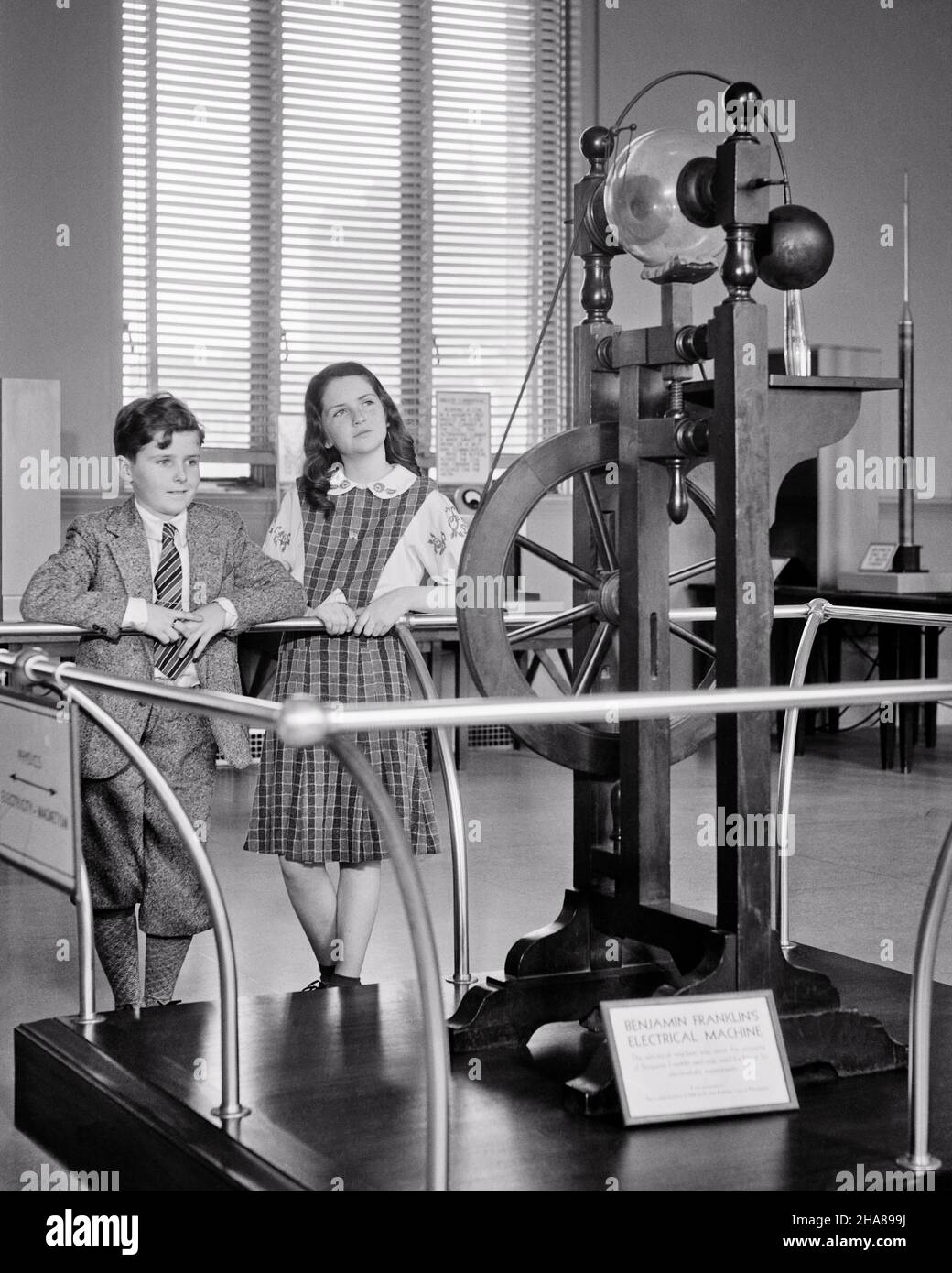 1930s BOY AND GIRL BROTHER AND SISTER AT SCIENCE MUSEUM LOOKING AT BEN ...