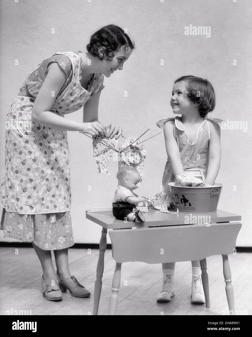 https://c8.alamy.com/comp/2HA89N1/1930s-little-girl-daughter-hand-washing-toy-doll-clothes-a-woman-her-mother-helping-by-hanging-them-to-dry-on-toy-clothesline-j6812-har001-hars-nostalgic-pair-domestic-her-mothers-dolls-wash-old-time-busy-teaching-nostalgia-old-fashion-1-household-juvenile-young-adult-teamwork-pleased-families-joy-lifestyle-satisfaction-chores-females-studio-shot-home-life-friendship-full-length-ladies-dry-daughters-persons-confidence-bw-brunette-homemaker-happiness-homemakers-cheerful-chore-housewives-smiles-tasks-connection-conceptual-joyful-support-growth-juveniles-moms-task-togetherness-2HA89N1.jpg