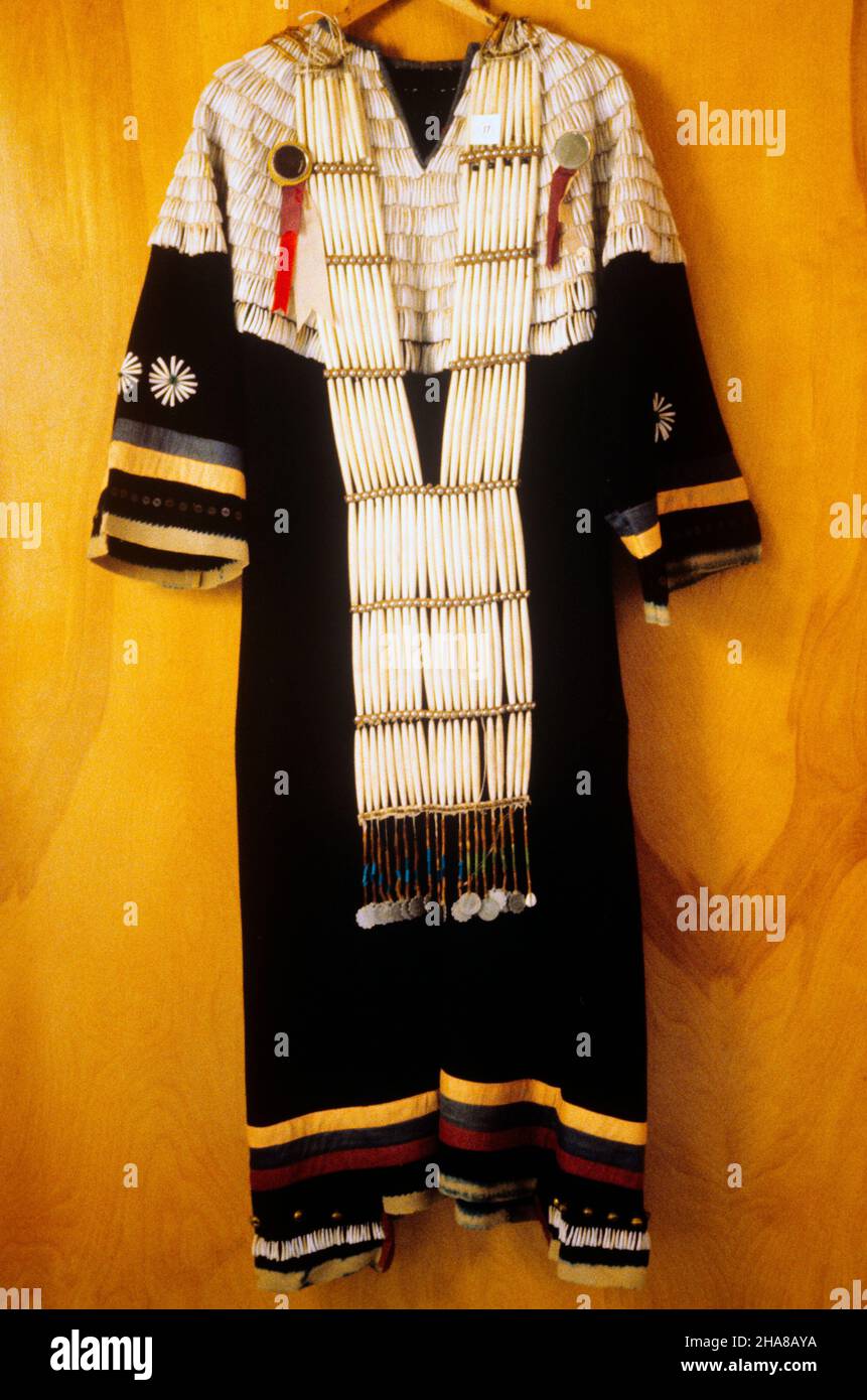 1900s NATIVE AMERICAN WOMAN’S TRADE CLOTH DRESS DECORATED WITH RIBBONS AND SHELLS AND A BREASTPLATE MADE OF BONE HAIR PIPES - ki11004 NAW001 HARS STILL LIFE STYLISH NATIVE AMERICAN CREATIVITY NATIVE AMERICANS RIBBONS CEREMONIAL INDIGENOUS OLD FASHIONED Stock Photo