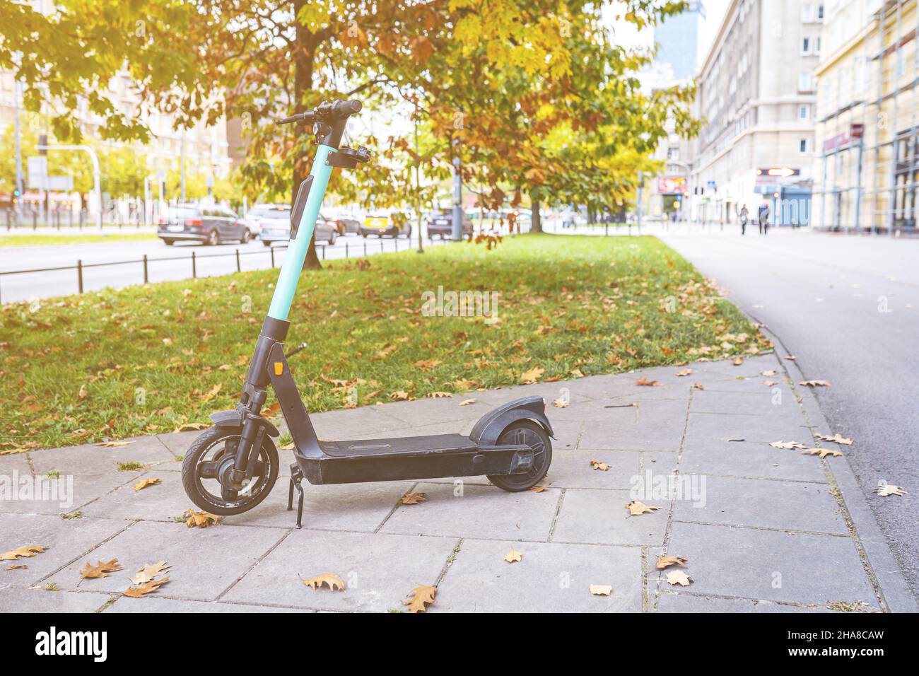 Rental electric scooter parked on city street. A green and black ride