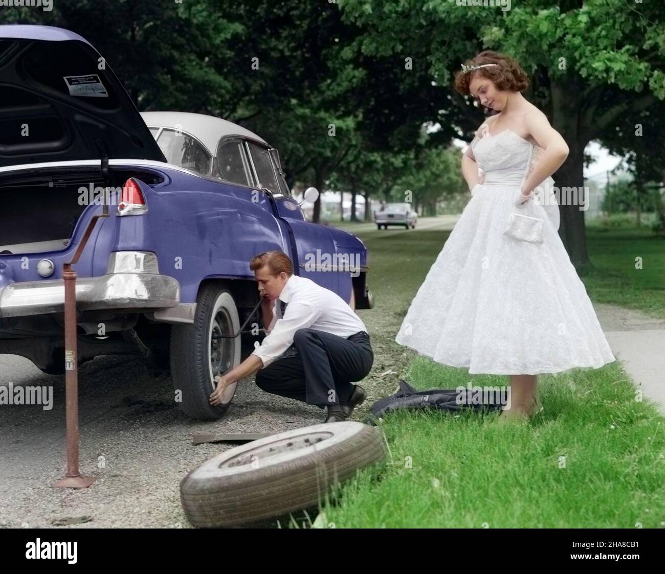 1950s TEENAGE BOY CROUCHING DOWN CHANGING FLAT TIRE PROM DATE WATCHING WITH HANDS ON HIPS - m3106c DEB001 HARS 1 JUVENILE ANGER TROUBLE CHANGING TIRE COPY SPACE FLAT FRIENDSHIP FULL-LENGTH AUTOMOBILE TEENAGE GIRL TEENAGE BOY TIARA TRANSPORTATION DATING DISASTER HUMOROUS MATE WHITEWALL EXCITEMENT UP ATTRACTION MOTORING STRAPLESS COURTSHIP MISHAP STYLISH TEENAGED WRECK DEB001 FLAT TIRE WHITEWALL TIRE CAR TROUBLE DRESSED UP MOTORIST POSSIBILITY CHANGING A FLAT JUVENILES PROM DATE PROM NIGHT SOCIAL ACTIVITY WELL-KEPT WELL-MAINTAINED WRECKAGE YOUNGSTER CAUCASIAN ETHNICITY COURTING OLD FASHIONED Stock Photo