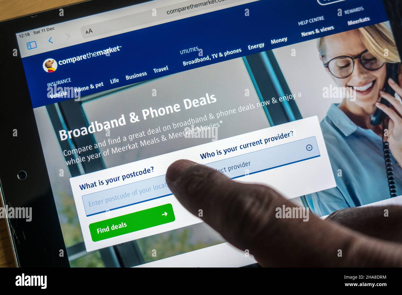 Broadband and Phone deals on CompareTheMarket site operated by Adult male finger on a portable device Stock Photo