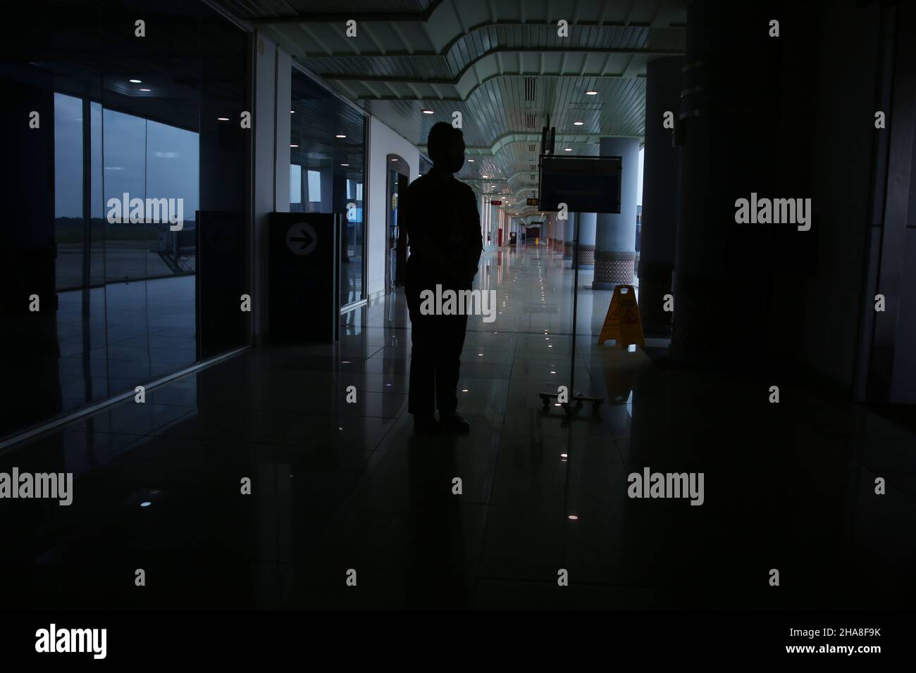 Palembang, South Sumatera, Indonesia. 11th Dec, 2021. Silhouette of an airport officer welcoming prospective passengers who will board the Bombardier CRJ 1000 aircraft belonging to PT Garuda Indonesia from Sultan Mahmud Badaruddin II Airport Palembang, South Sumatra to Soekarno Hatta Airport, Jakarta, Indonesia. The Bombardier CRJ1000 was developed by Bombardier Aerospace, a Canadian-based company. This aircraft is equipped with a system that can make the aircraft avoid collisions, as well as check the weather in the area and the intended crossing, it is also claimed to be a fuel-efficient Stock Photo