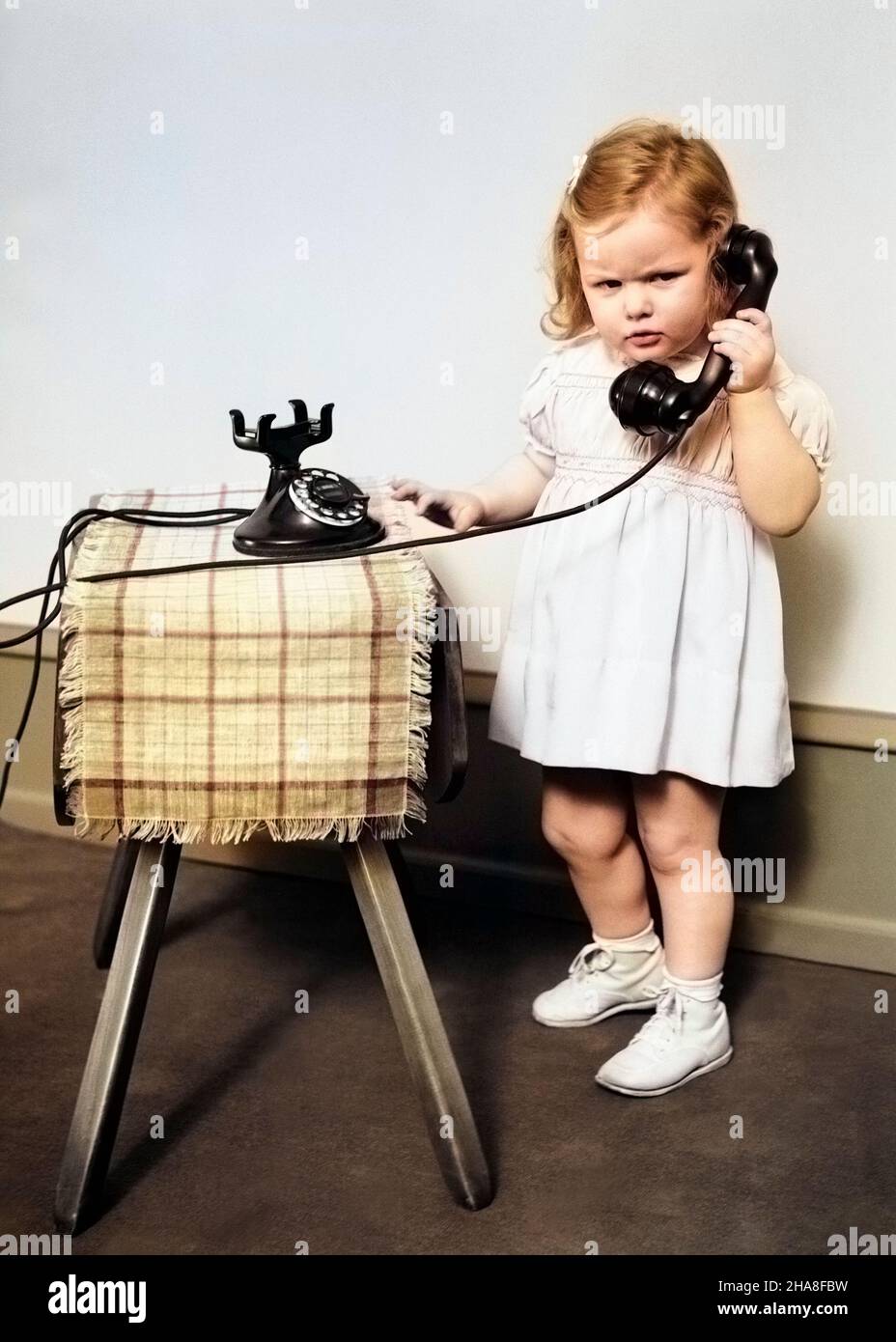 1930s 1940s UNHAPPY FROWNING LITTLE GIRL TALKING ON OLD BLACK ROTARY DIAL TELEPHONE - t5516c HAR001 HARS CAUCASIAN ETHNICITY HAR001 OLD FASHIONED Stock Photo