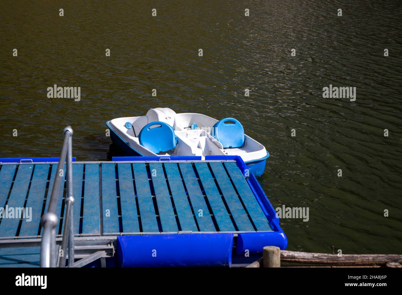 Single plastic pedal boat moored to a plastic jetty in the water Stock Photo