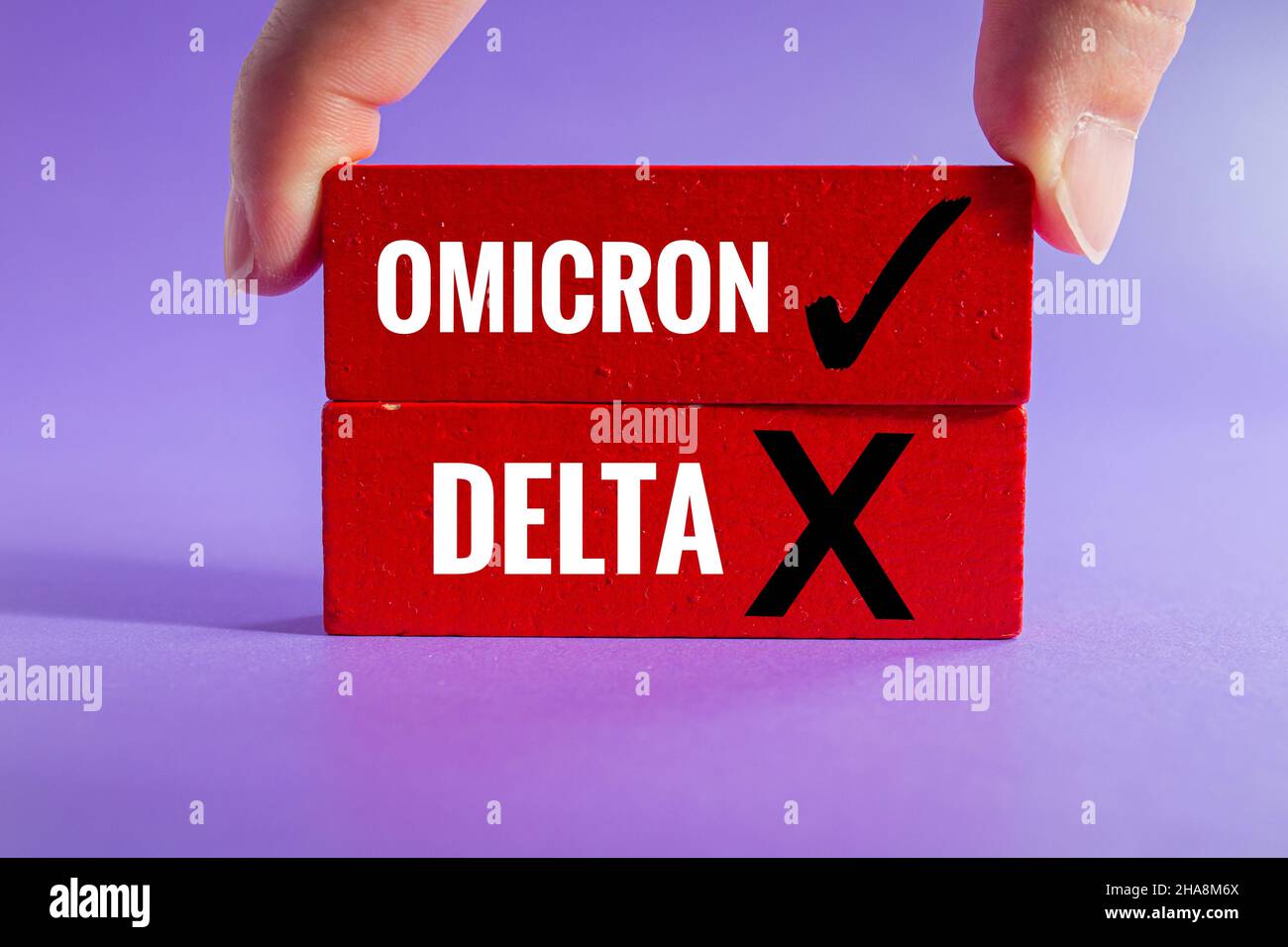 Covid-19 Omicron variant concept, hand adds wooden block to stack. Delta variant out, Omicron in. Stock Photo