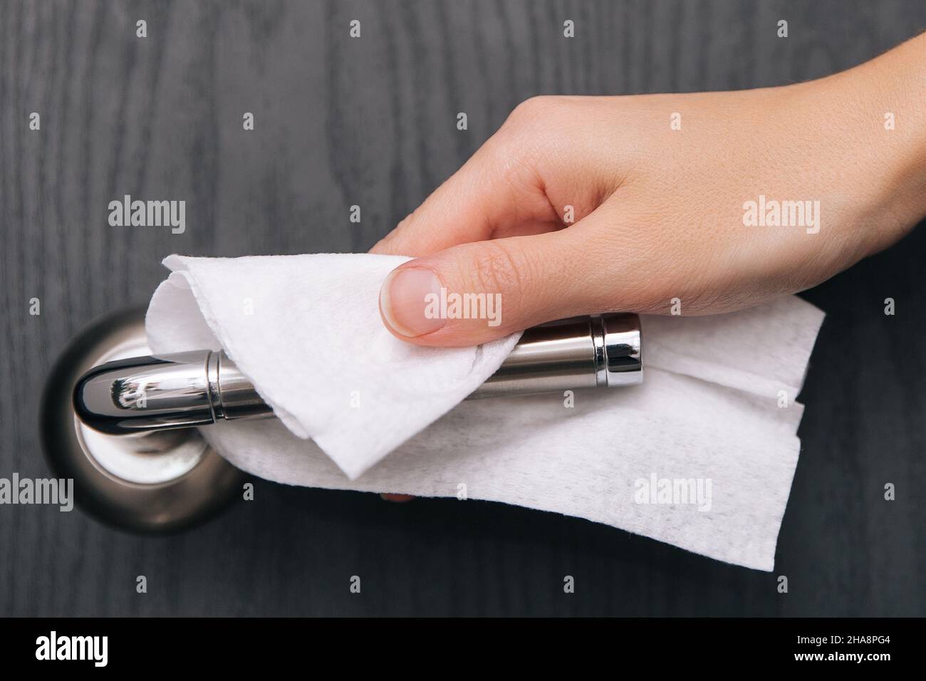 Cleaning black door handles with an antiseptic wet wipe. Sanitize surfaces prevention in