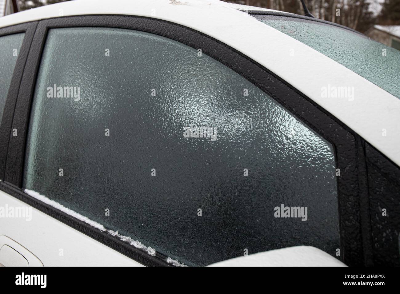 Layer of ice rain covering car glass window on cold winter day outdoors. Extreme weather