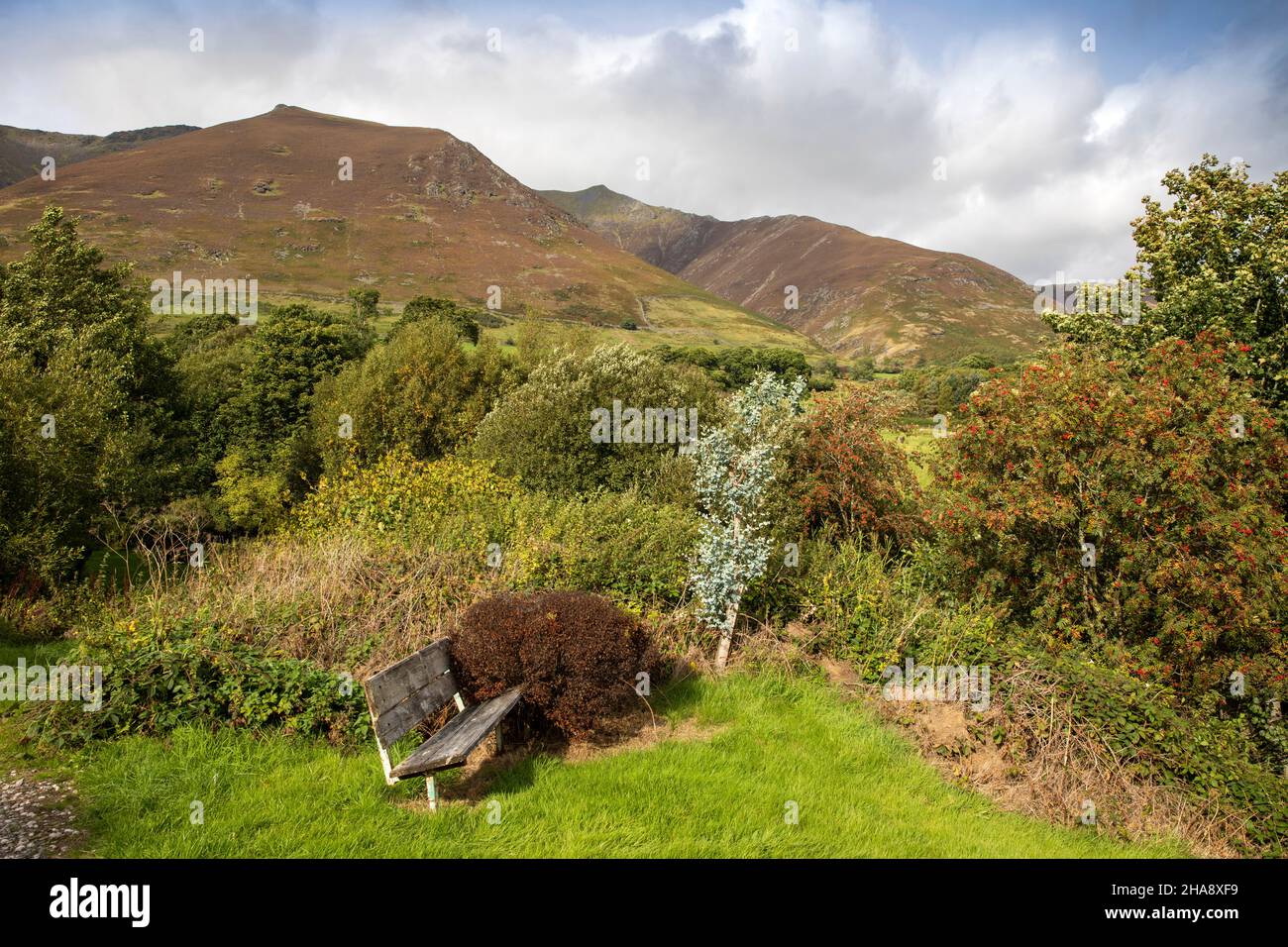 UK, Cumbria, Allerdale, Keswick, Threlkeld, public bench in garden below Blencathra ‘Saddleback’ hill Stock Photo
