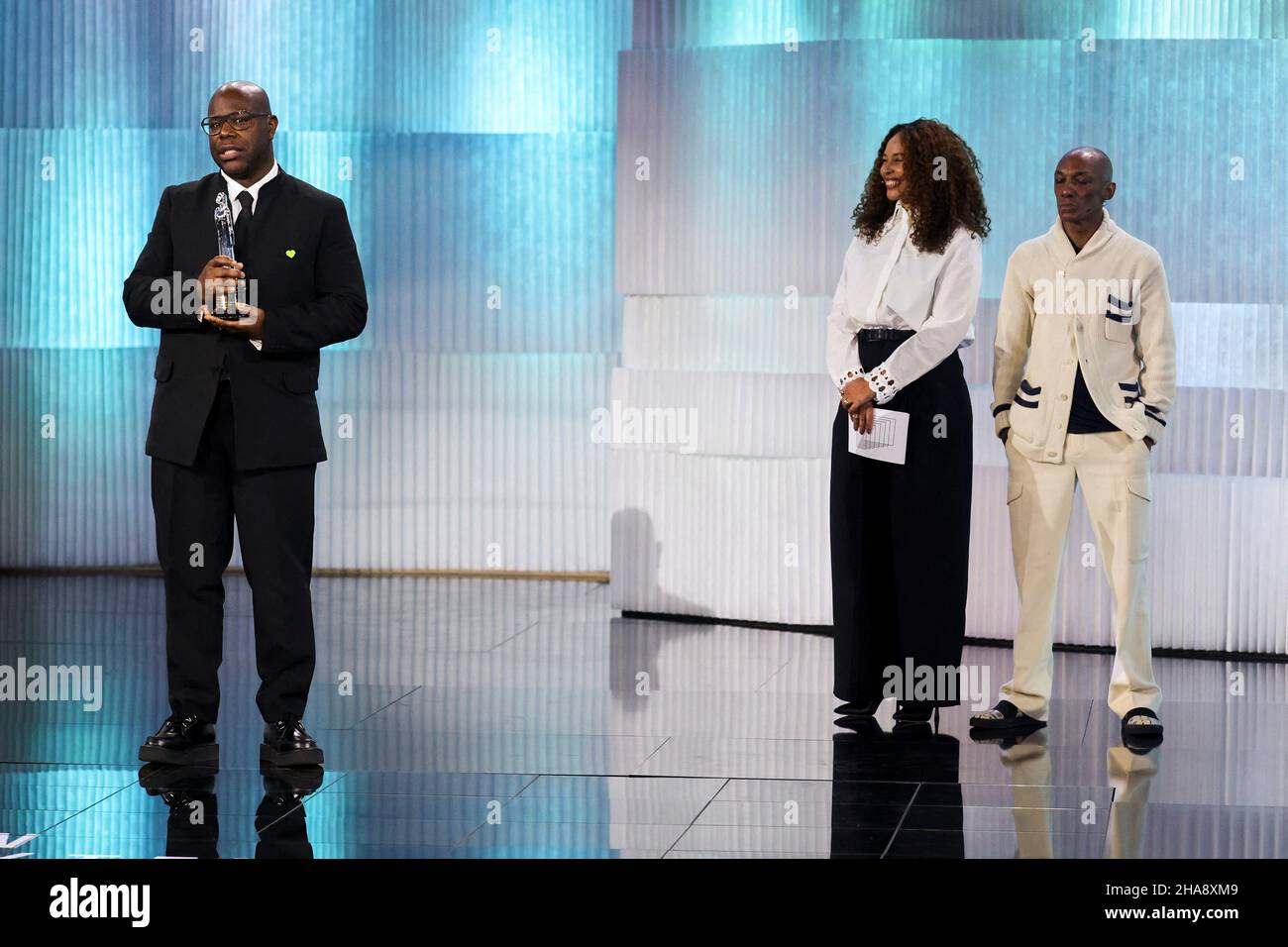 Berlin, Germany. 11th Dec, 2021. Steve McQueen (l) receives the award for innovative storytelling for 'Small Axe' at the 34th European Film Awards. The European Film Academy presents the awards in Berlin. Joy Denalane is on stage in the middle. Credit: Christian Mang/Reuters/Pool/dpa/Alamy Live News Stock Photo