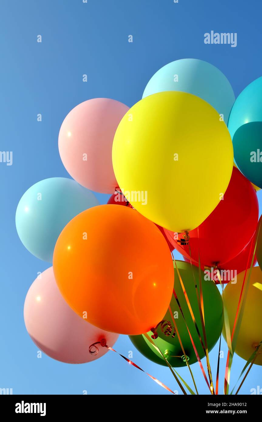bunch of multicolored balloons in the city festival on clear blue sky background, vertical composition Stock Photo