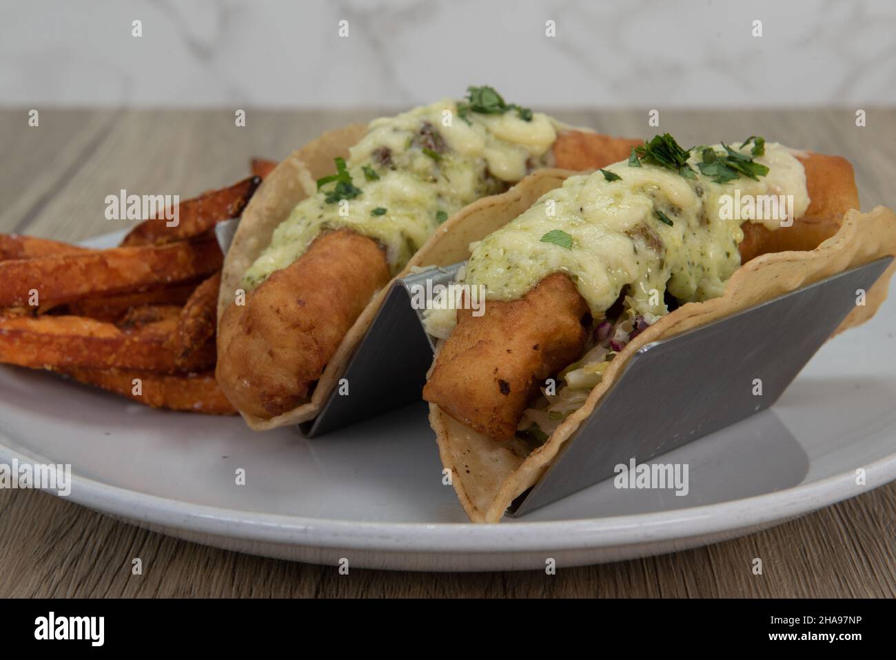 Artistic presentation of crispy deep fried fish tacos covered in melted