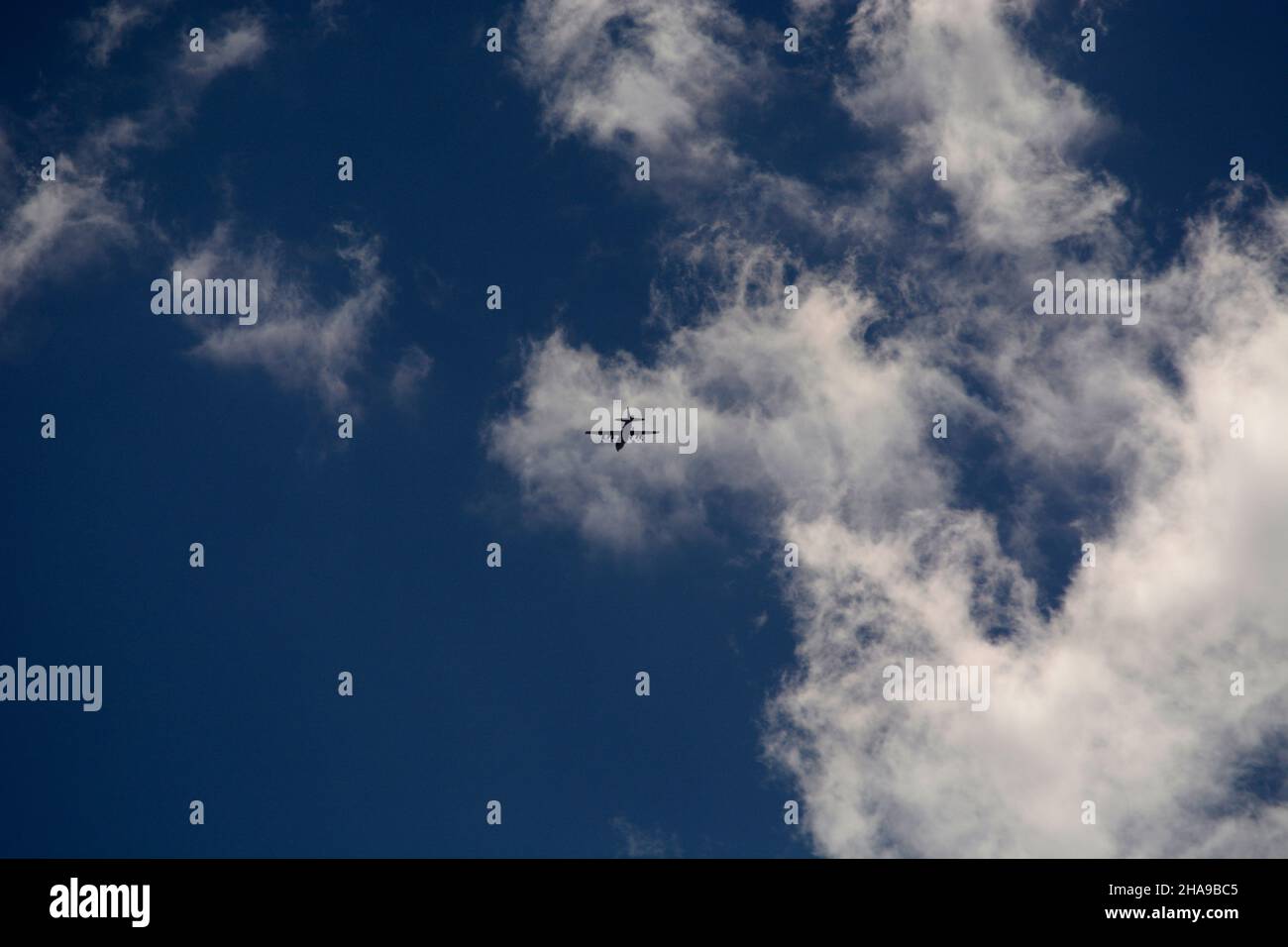 A Lockheed C130 Hercules military cargo aircraft flies through clouds