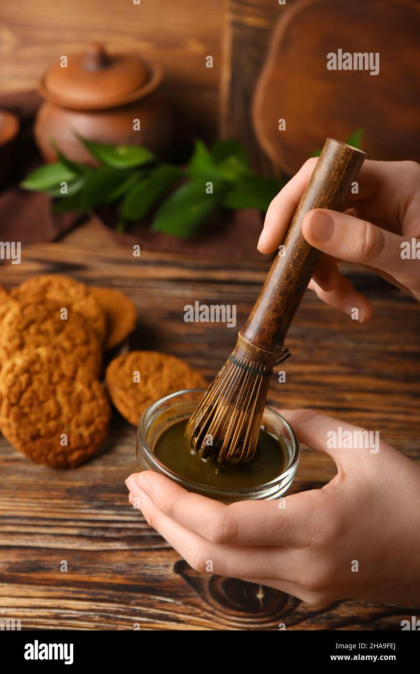 https://c8.alamy.com/comp/2HA9FEJ/woman-preparing-green-hojicha-tea-on-wooden-background-closeup-2HA9FEJ.jpg