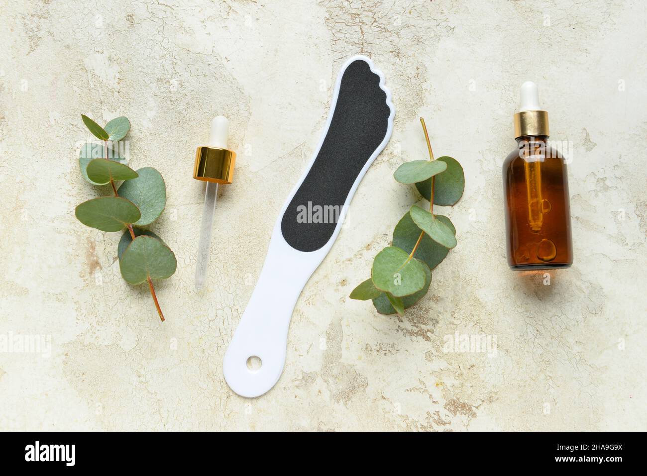 Foot file for massage, bottle of essential oil and eucalyptus branches