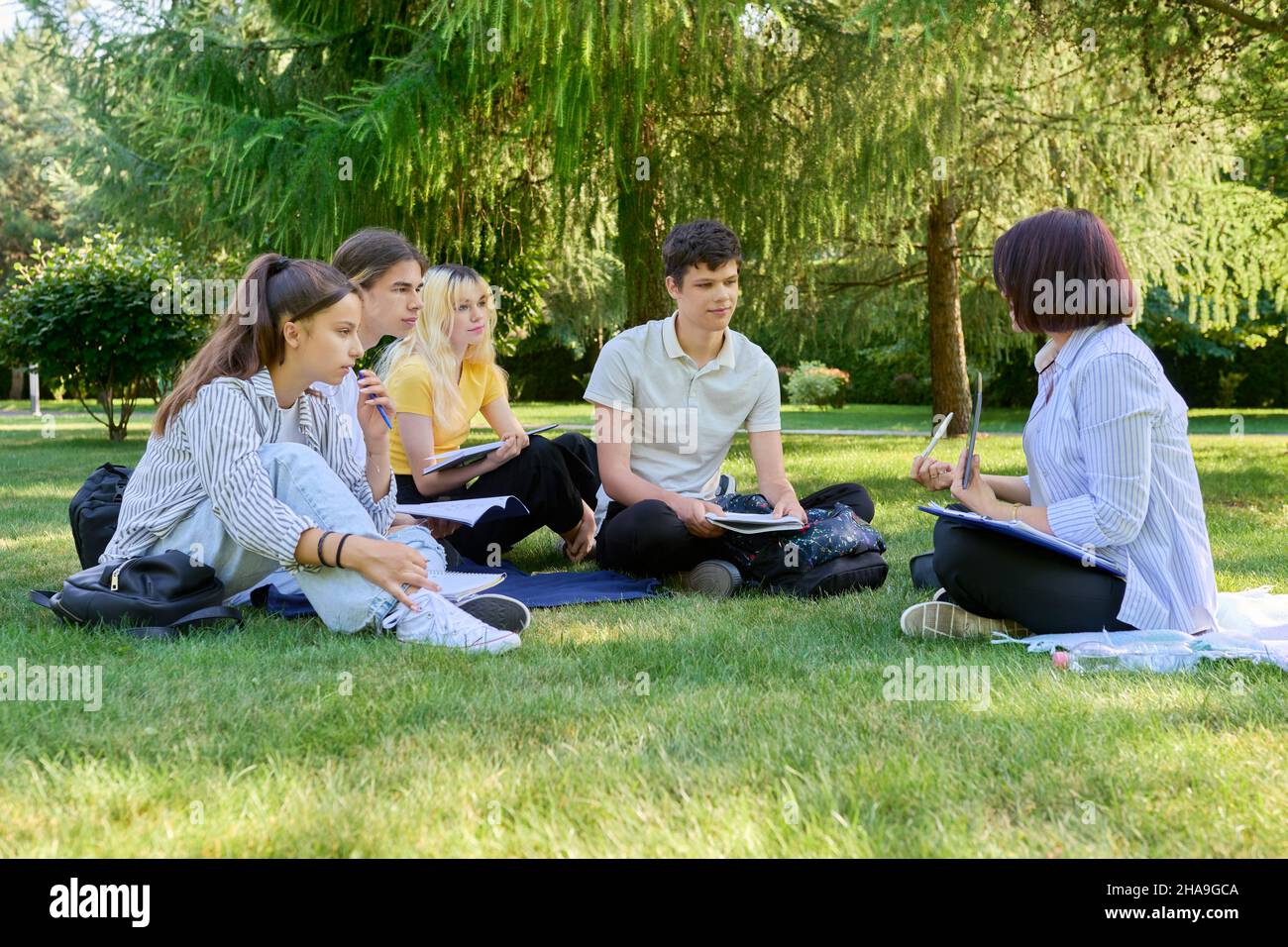 Outdoor, group of students with female teacher sitting on grass Stock ...
