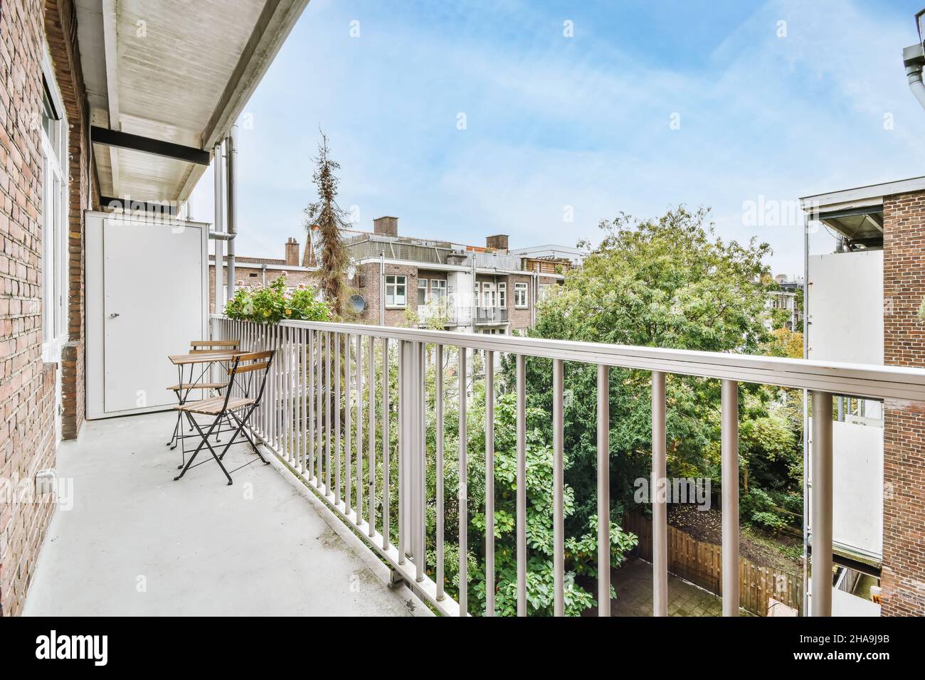 Elegant narrow and long balcony with wooden table and chairs Stock