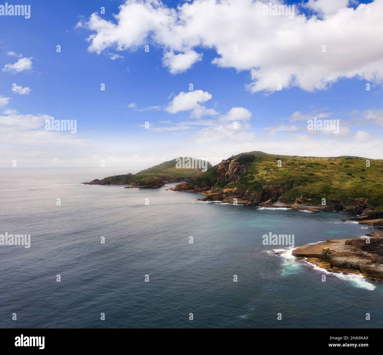 Eroded cliffs of Broughton island on Australian Pacific coast facing open ocean in aerial seascape view. Stock Photo