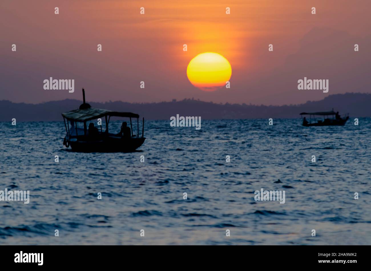 Sunset seen from Ribeira beach in Salvador, Bahia, Brazil. A boat sails at sea. Stock Photo