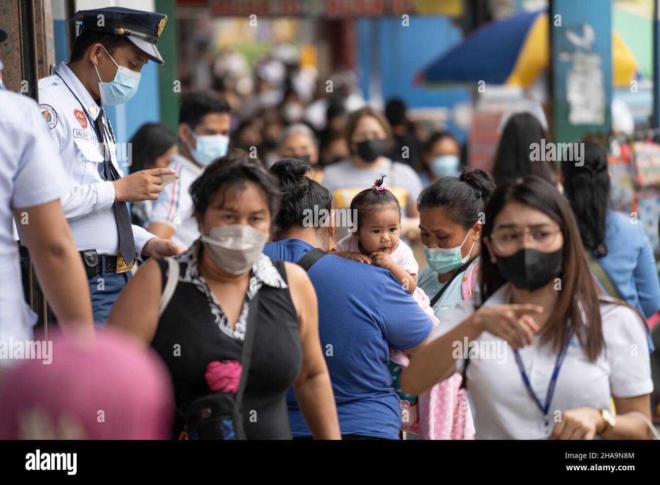 A security guard checking identity documents of an adult holding a child before being allowed to enter retail premises, Cebu City, Philippines Stock Photo