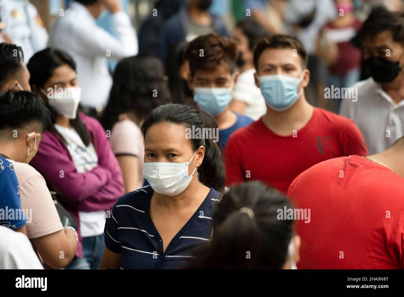People in the Philippines walking along a street wearing face masks, the wearing of face masks in public places and establishments is mandatory. Stock Photo