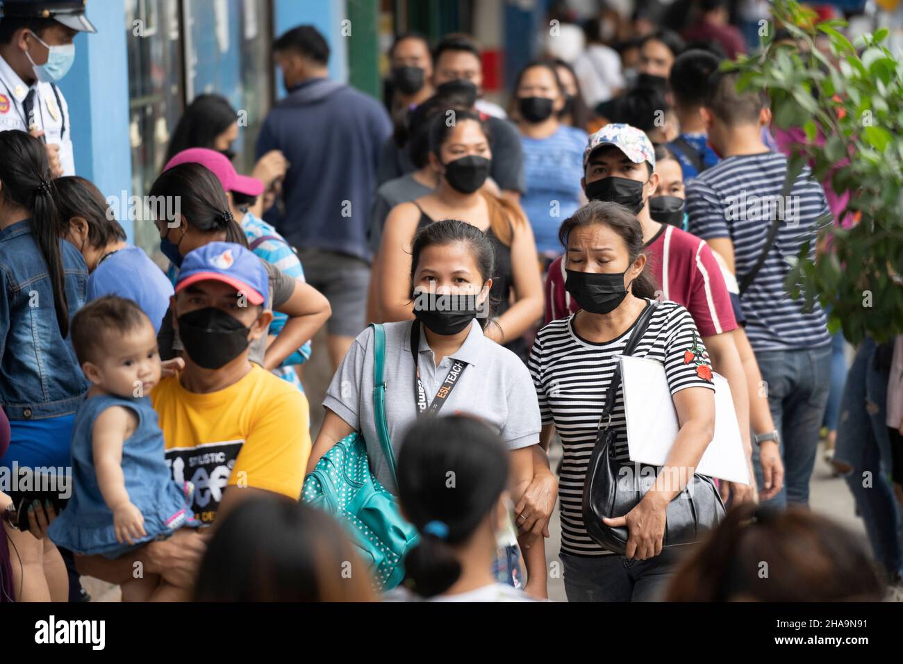 People in the Philippines walking along a street wearing face masks, the wearing of face masks in public places and establishments is mandatory. Stock Photo
