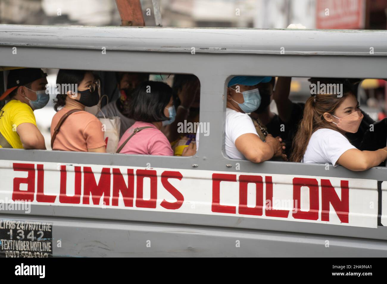 Commuters in the Philippines wearing face masks as they ride a public transport vehicle known as a multicab. Stock Photo