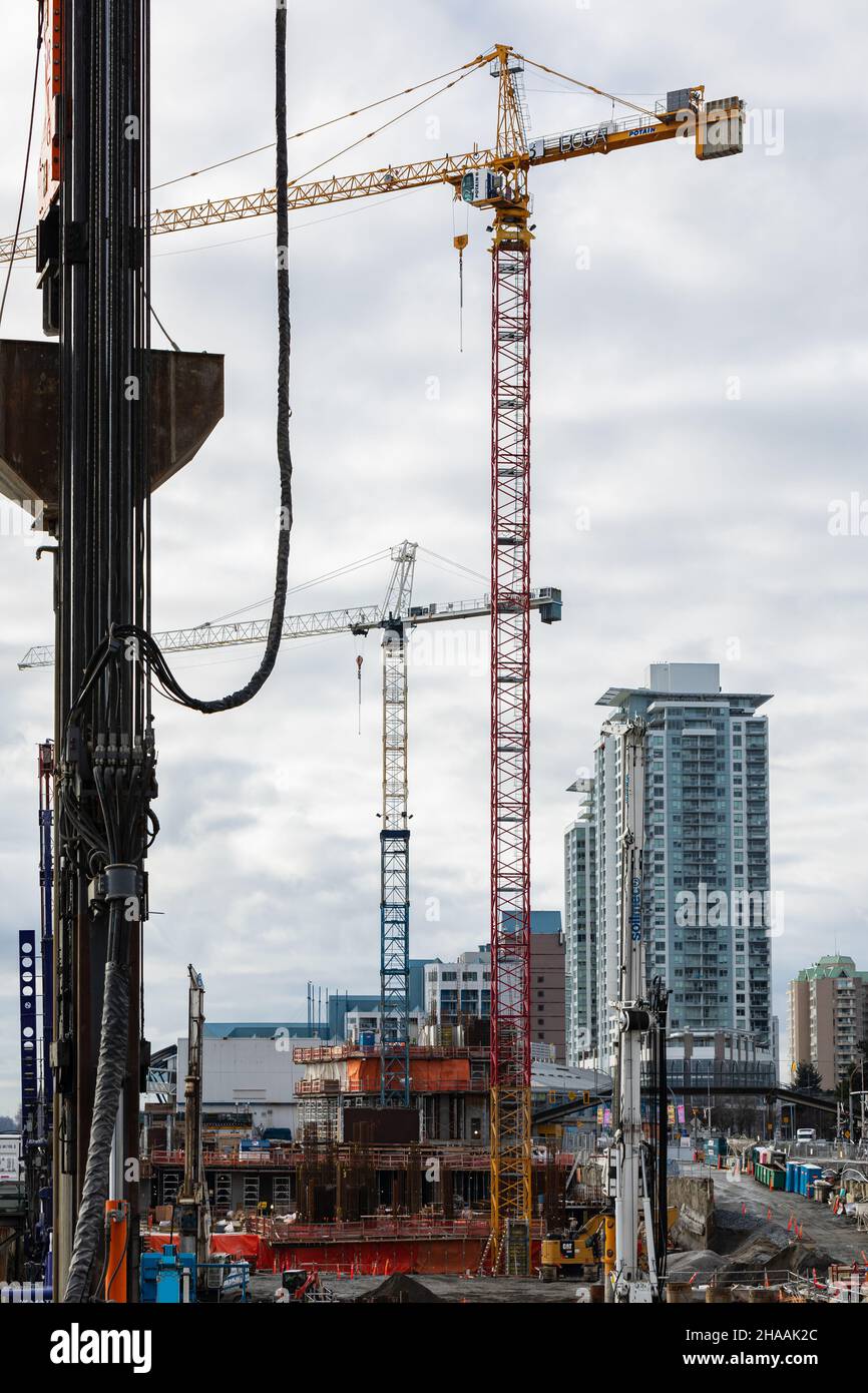 Industrial landscape with construction cranes on dramatic cloudy sky background. Building construction site with industrial cranes in New Westminster Stock Photo