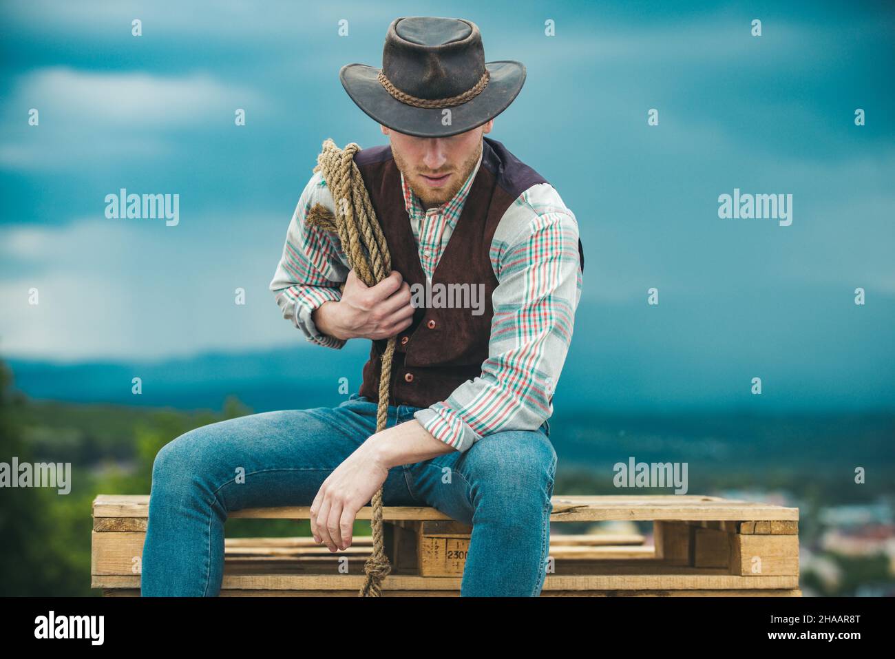 American cowboy man. Cowboy with lasso rope on sky background. Brutal ...