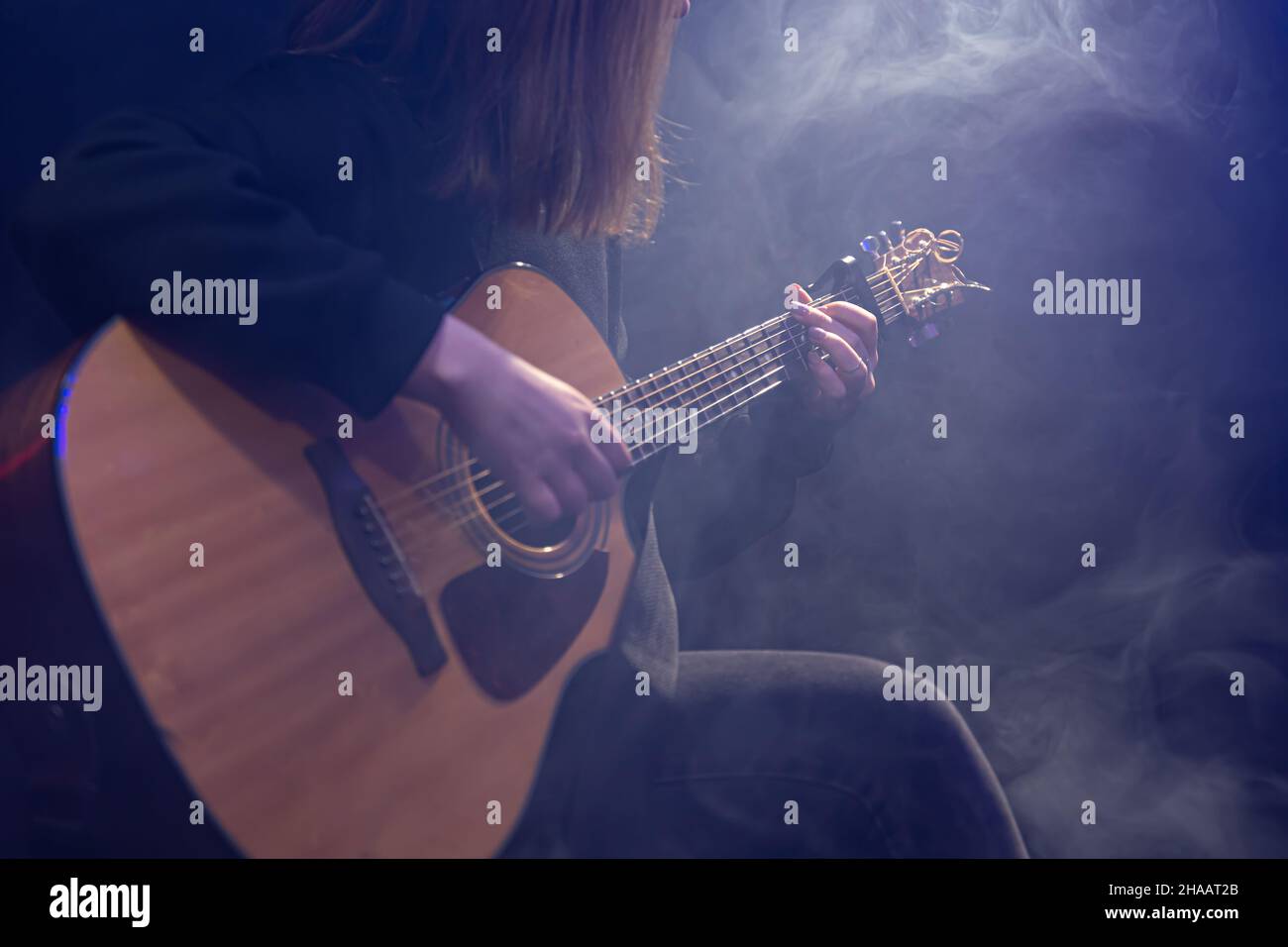 Young woman playing acoustic guitar in a dark room with haze Stock ...