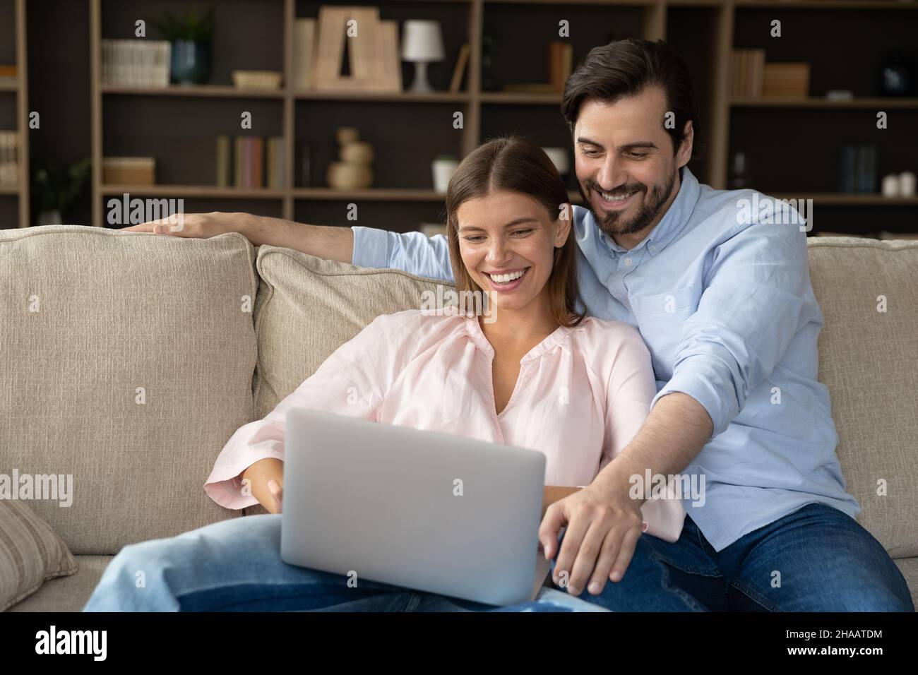 Joyful happy married couple relaxing at laptop on couch Stock Photo
