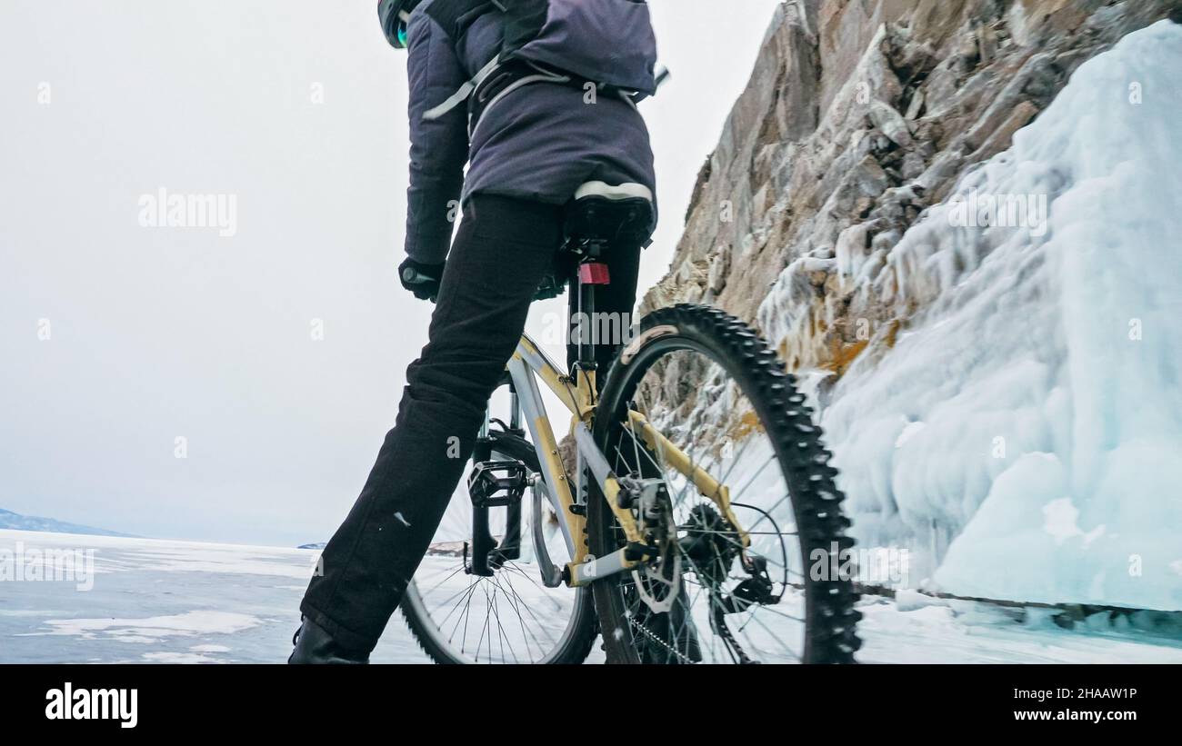 Man is riding bicycle near ice grotto. Rock with ice caves icicl Stock Photo
