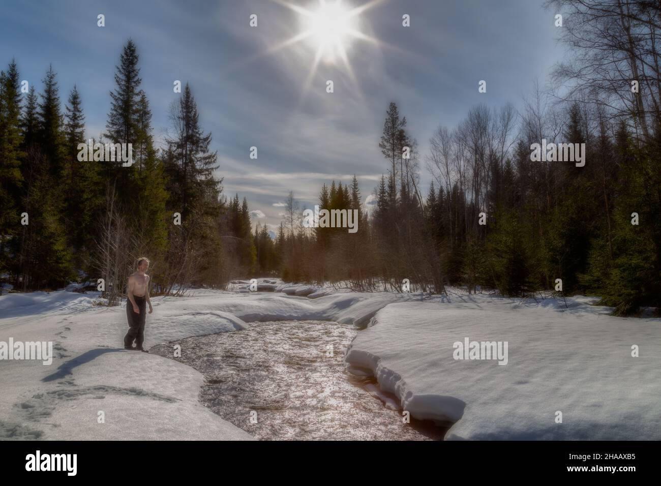 man and a river with ice and snow in a forest Stock Photo