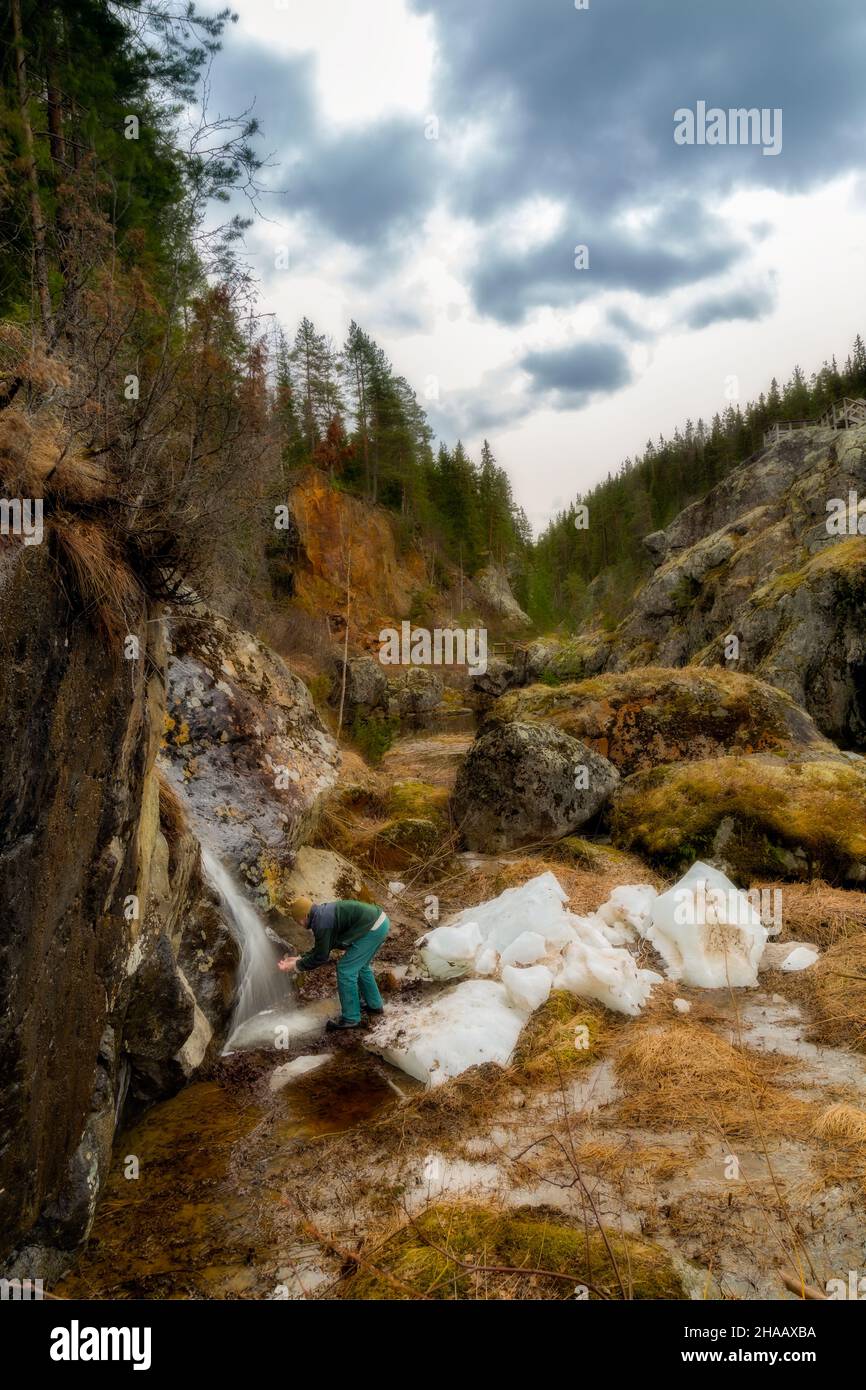 man and a waterfall with ice and snow in a rocky forest Stock Photo
