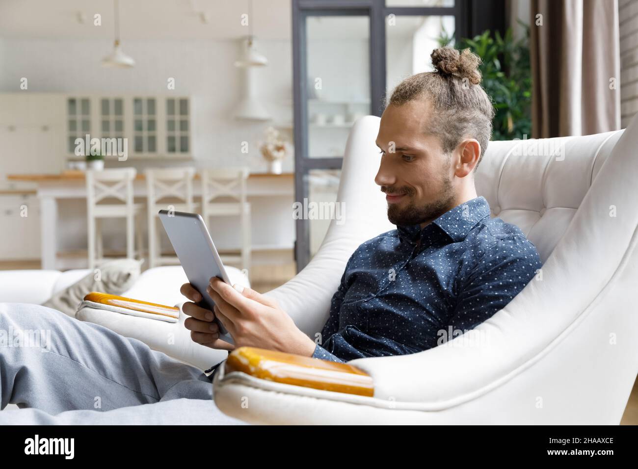Smiling gadget user man reading book on tablet computer screen Stock Photo