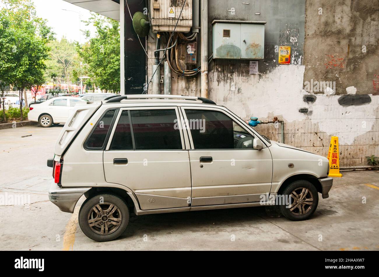 A Jiangnan T11, a Chinese made electrified version of the second generation Suzuki Alto, being charged by a jury rigged cable from a second floor wind Stock Photo